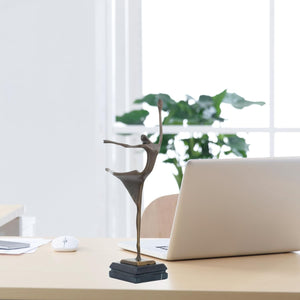 Abstract bronze ballerina dancer sculpture on office desk alongside laptop as art collection display
