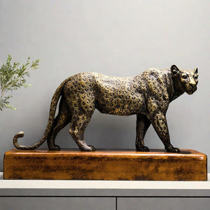 Front angle view of antique bronze leopard sculpture with greenery styled in indoor decor setting