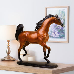 Chestnut amber Arabian stallion bronze sculpture displayed beside lamp and framed wall art