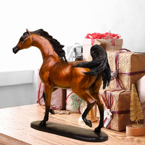 Chestnut amber Arabian stallion bronze sculpture displayed beside gift boxes and floral decor