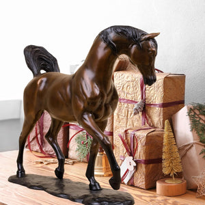 Antique chestnut Arabian stallion bronze sculpture displayed on table beside decorative wooden bowls