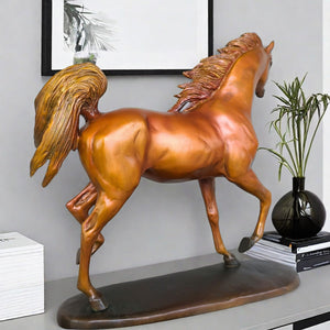 Arabian stallion bronze sculpture in gold-brown finish displayed on table beside vase and plant