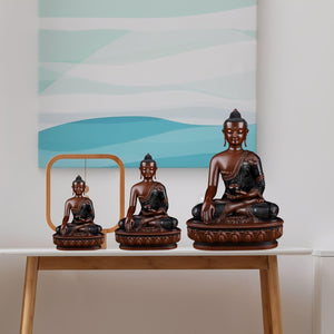 Bhumisparsha Buddha red copper statue in two sizes displayed on wooden desk with blue background
