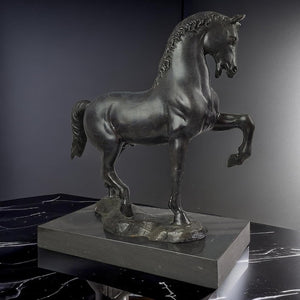 Black bronze striding stallion statue side view displayed against dark moody background