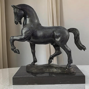 Black bronze striding stallion statue displayed indoors with curtain background lifestyle setting