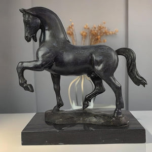 Black bronze striding stallion statue back angle view displayed with warm indoor lighting