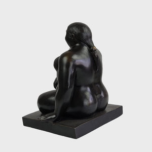 Botero bronze seated woman sculpture three quarter angle dark background