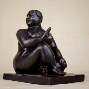 Close-up face detail of Botero style seated bronze fat woman sculpture showing serene expression