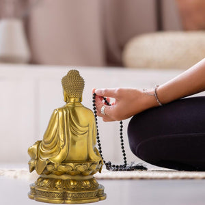 Brass Buddha statue in meditation lifestyle scene beside woman practicing zen relaxation