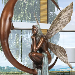 Bronze fairy crescent moon sculpture displayed in living room beside floor lamp
