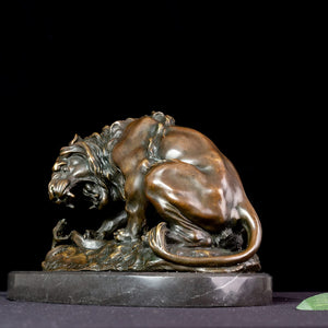 Close-up side view of dark patina bronze lion and serpent Barye masterpiece sculpture on marble base