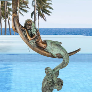 Bronze mermaid crescent moon sculpture displayed poolside luxury resort setting