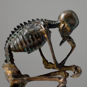 Bronze skeleton Thinker statue in antique grey bronze finish front view on white background