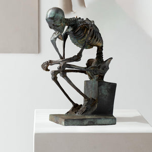 Bronze skeleton Thinker statue in antique grey bronze finish front view on white background
