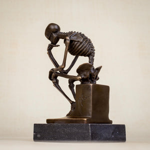 Bronze skeleton Thinker statue in brown bronze finish front view on beige background