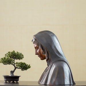 Bronze Virgin Mary bust statue side view displayed alongside bonsai tree in lifestyle setting
