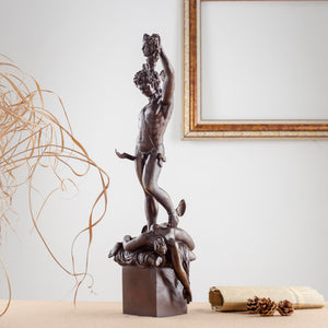 Cellini Perseus Medusa green bronze sculpture displayed beside fireplace in luxury interior