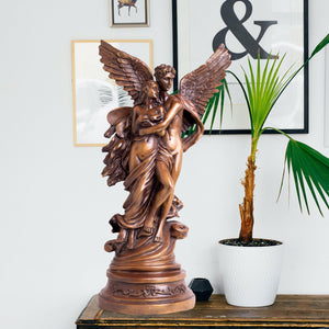 Cupid Psyche bronze sculpture displayed in warm interior beside plant natural light