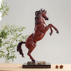 Red bronze rearing stallion sculpture angle view displayed with greenery decor