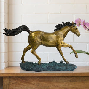 22-inch galloping bronze horse sculpture golden stallion with black mane displayed on wooden console with floral decor