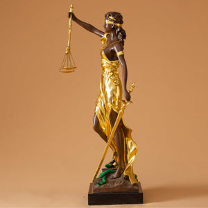 Close-up detail of gilded bronze Lady Justice Themis statue showing gold patina finish and scales