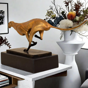 Close-up detail of gold running cheetah sculpture on black marble base in indoor decor