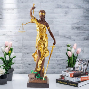 Large gold bronze Lady Justice Themis statue displayed against outdoor white wall front view