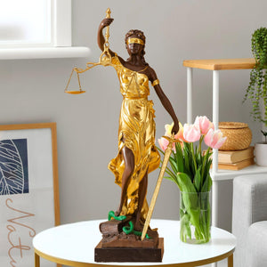 Large gold bronze Lady Justice Themis statue on side table styled with floral arrangement in home decor