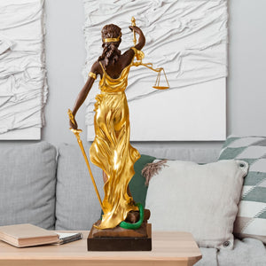 Large gold bronze Lady Justice Themis standing statue in indoor white wall modern setting