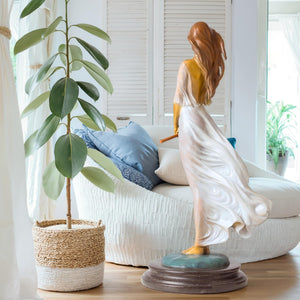 Luo Li Rong silk dancer bronze statue white dress marble base displayed beside indoor plant natural light