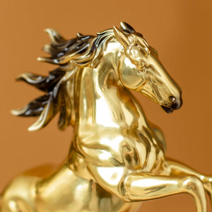 Close-up detail of radiant gold rearing horse bronze sculpture head showing polished gold finish