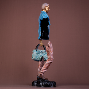 Modern bronze sculpture of a man with blue jacket and bag, abstract design, standing pose