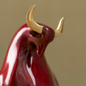 Artistic red enamel glaze texture on charging bull figurine.