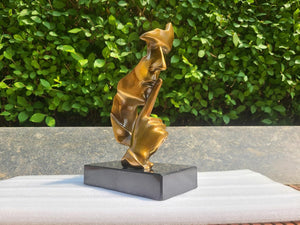 Left angle view of gold Silence is Gold thinker bronze figurine on outdoor marble base