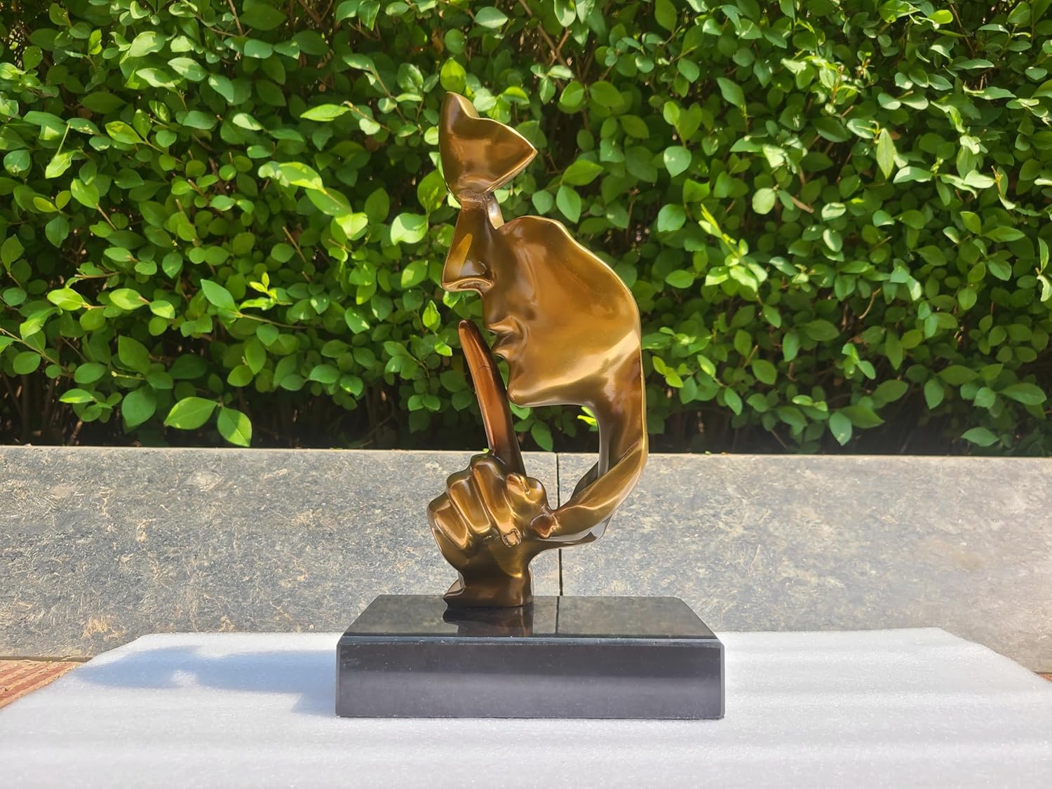 Silence is Gold abstract thinker sculpture gold finish displayed outdoors on marble base