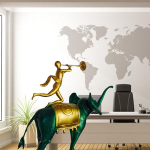 Surrealist bronze elephant statue on desk beside vintage globe and world map decor
