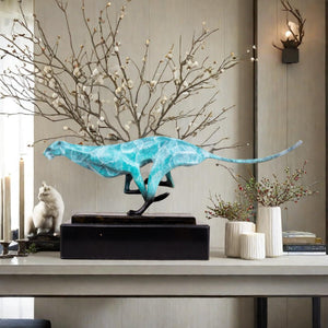 Teal azure running cheetah sculpture on marble base styled with dried branch in luxury interior