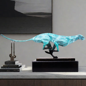 Teal azure running cheetah sculpture on marble base in indoor luxury home decor setting
