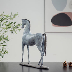 White bronze minimalist horse sculpture side view displayed with modern art and decorative pinecones
