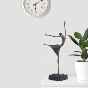 Abstract bronze ballerina dancer sculpture front full body view displayed with indoor plant decor