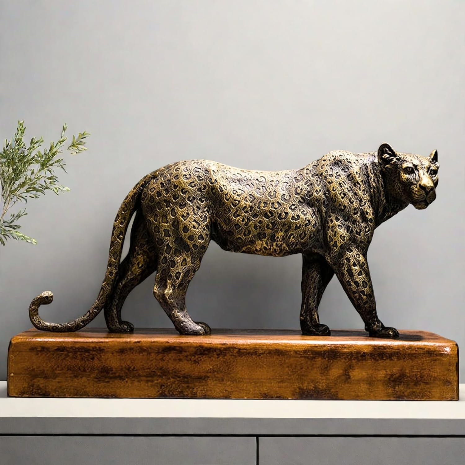 Front angle view of antique bronze leopard sculpture with greenery styled in indoor decor setting