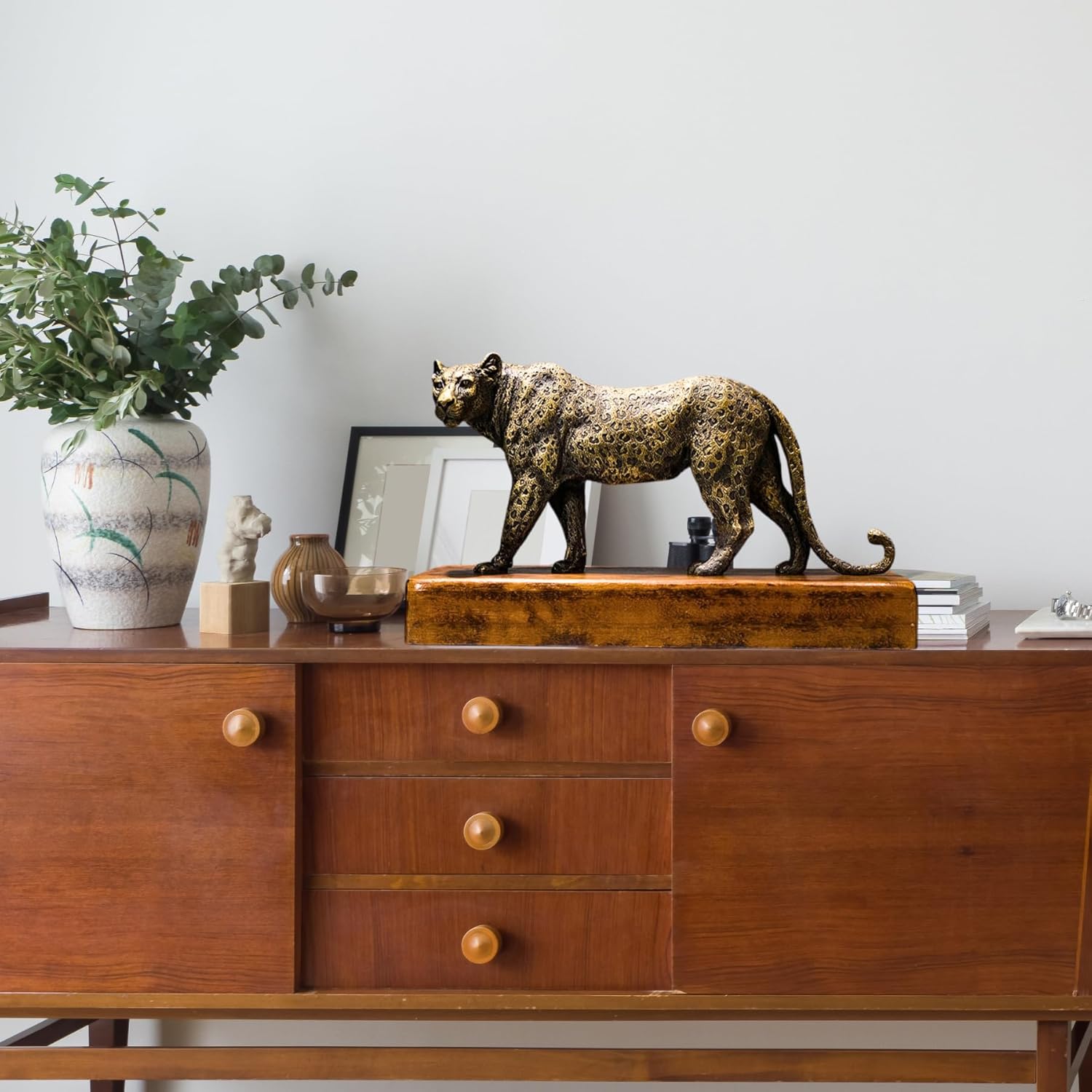 Antique bronze leopard statue styled on wooden cabinet in modern living room decor setting