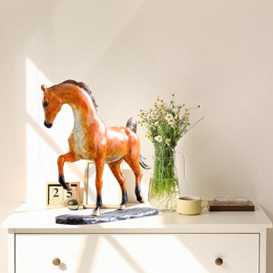 Arabian horse bronze sculpture displayed on table beside decorative vase with greenery