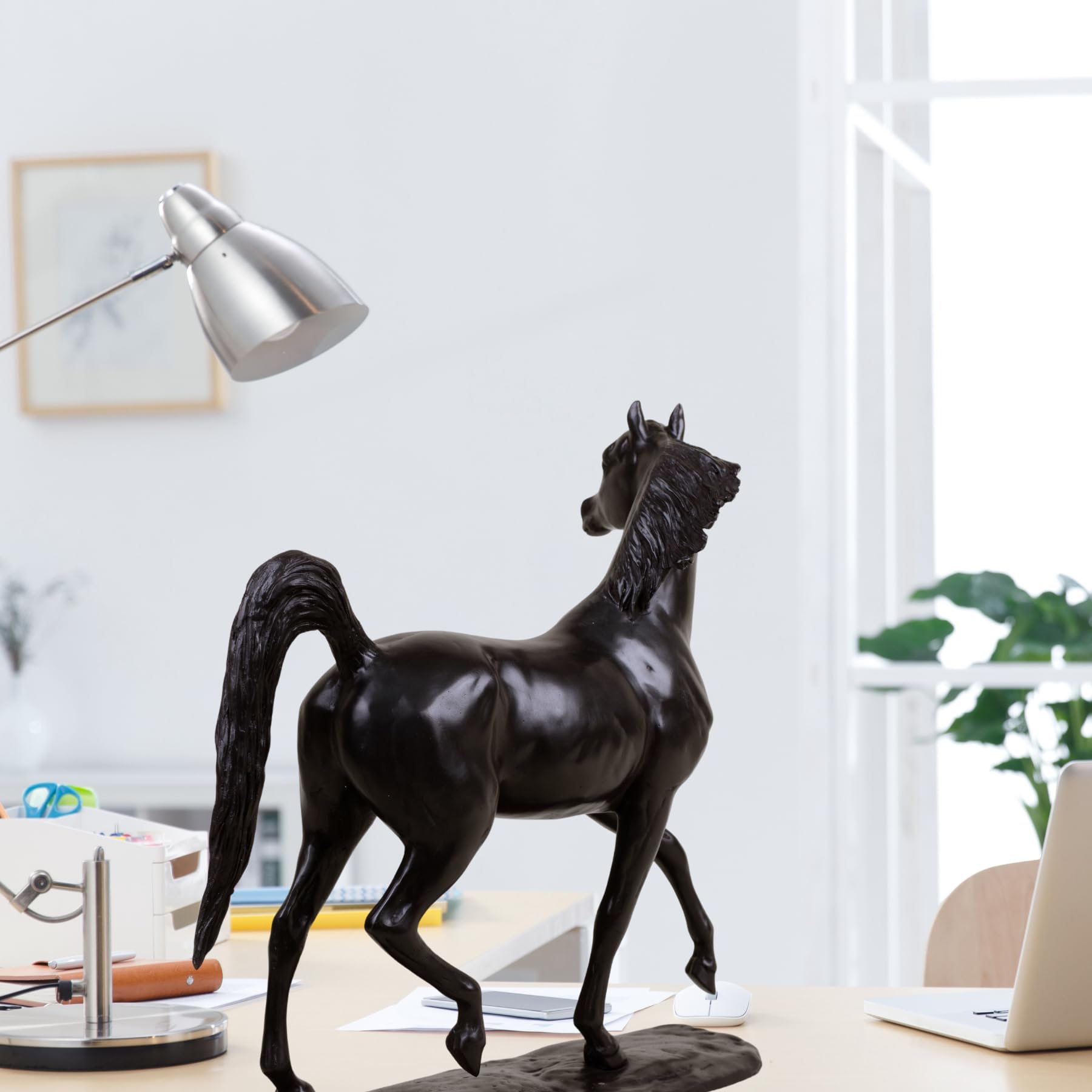 Midnight black Arabian stallion bronze sculpture on desk beside lamp and office supplies
