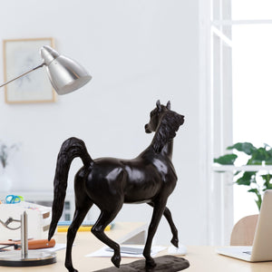 Midnight black Arabian stallion bronze sculpture on desk beside lamp and office supplies