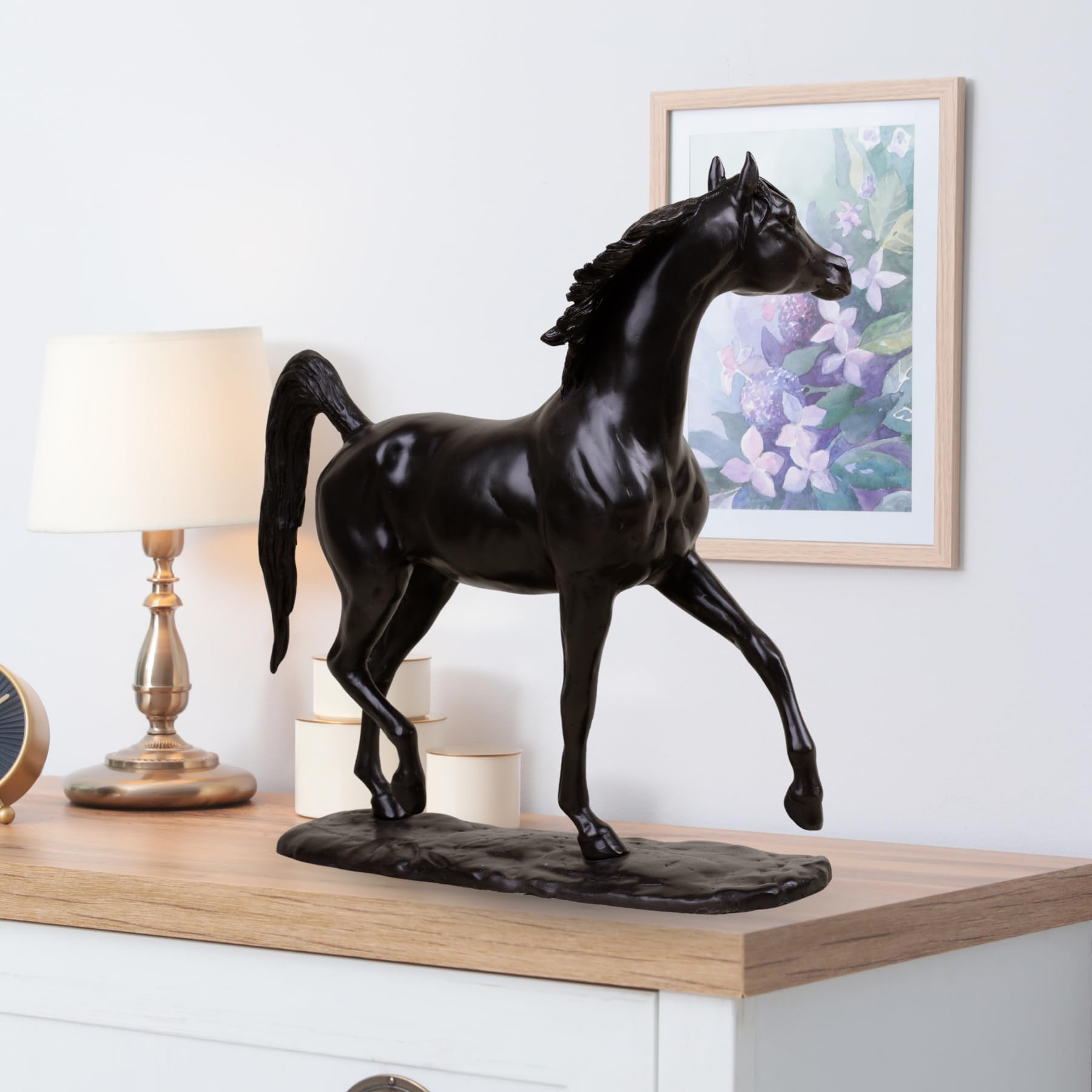 Midnight black Arabian stallion bronze sculpture displayed on table beside lamp and framed art