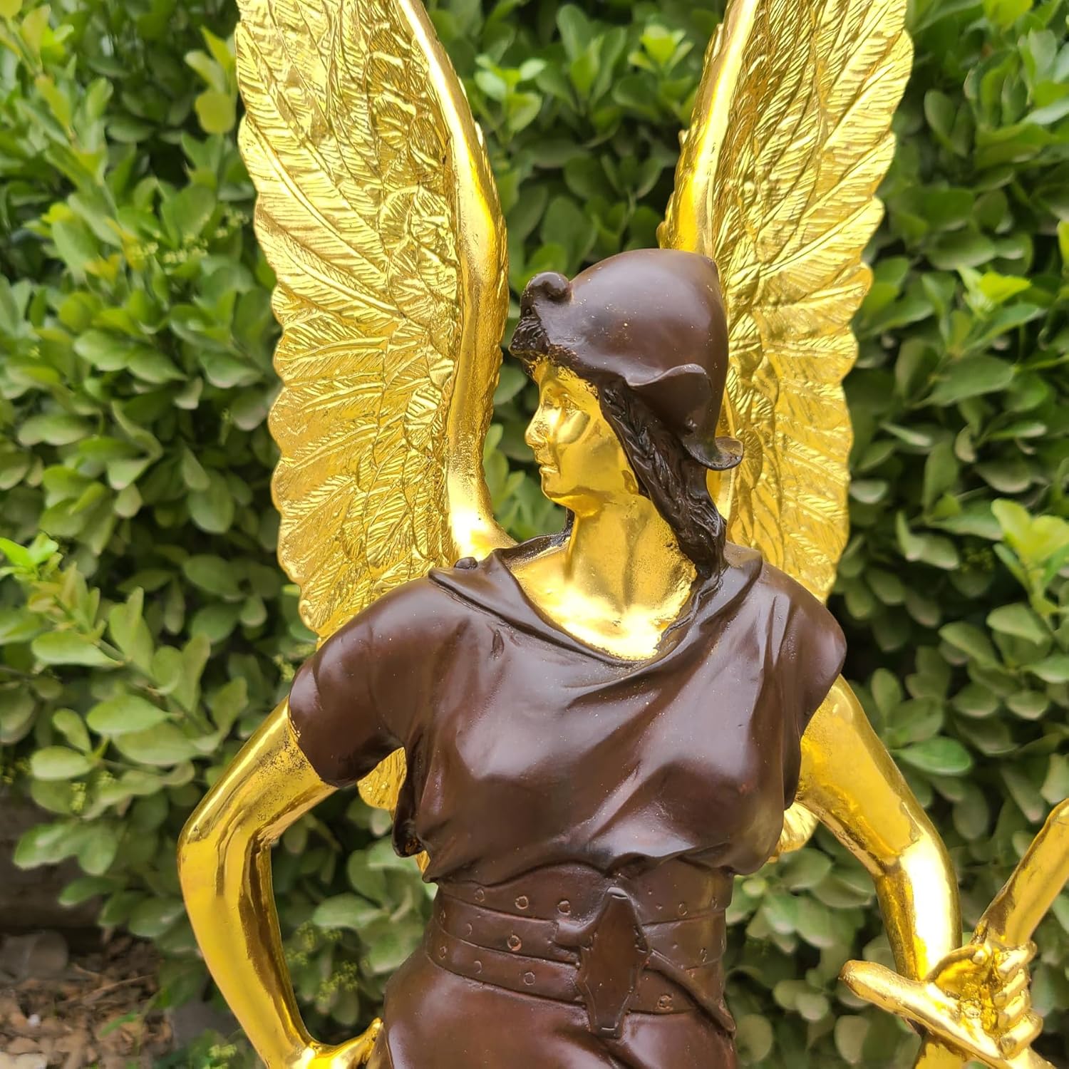 Close-up of Athena bronze goddess face and upper body detail with gold angel wing texture