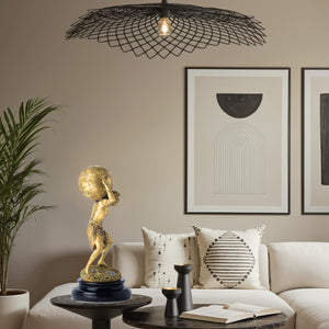 Atlas bronze sculpture gold finish displayed beside luxury armchair interior