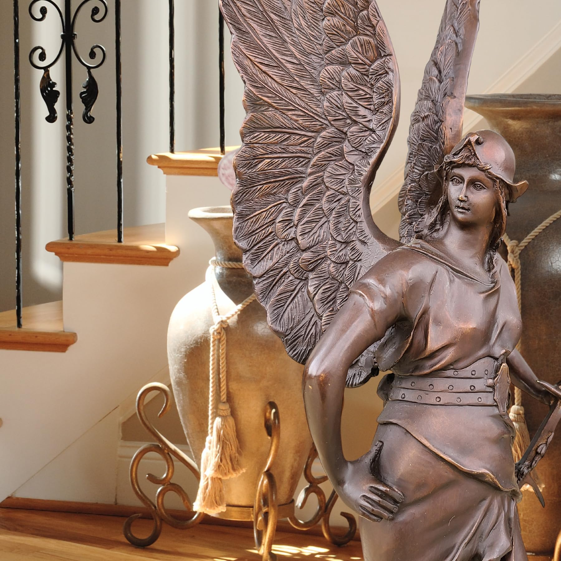 Classic bronze Bellona winged goddess statue in outdoor garden setting with natural backdrop