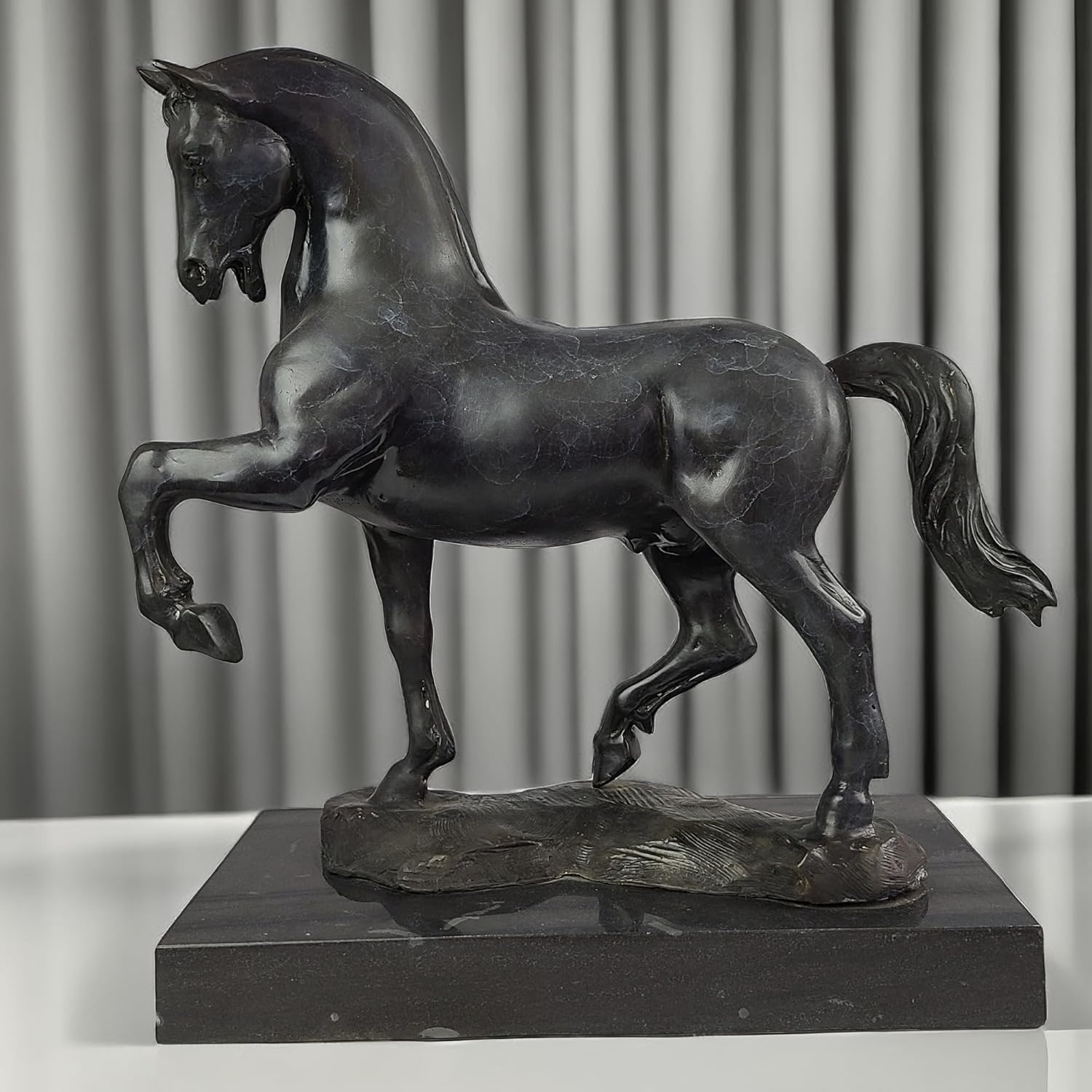 Black bronze striding stallion statue front angle view displayed with curtain background